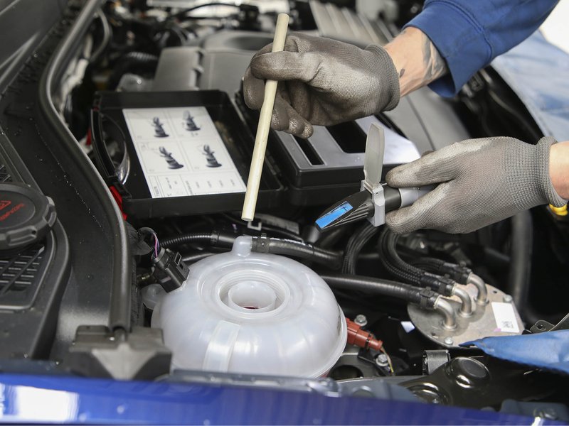 Motorraum eines Autos, bei dem Bremsflüssigkeit nachgefüllt wird